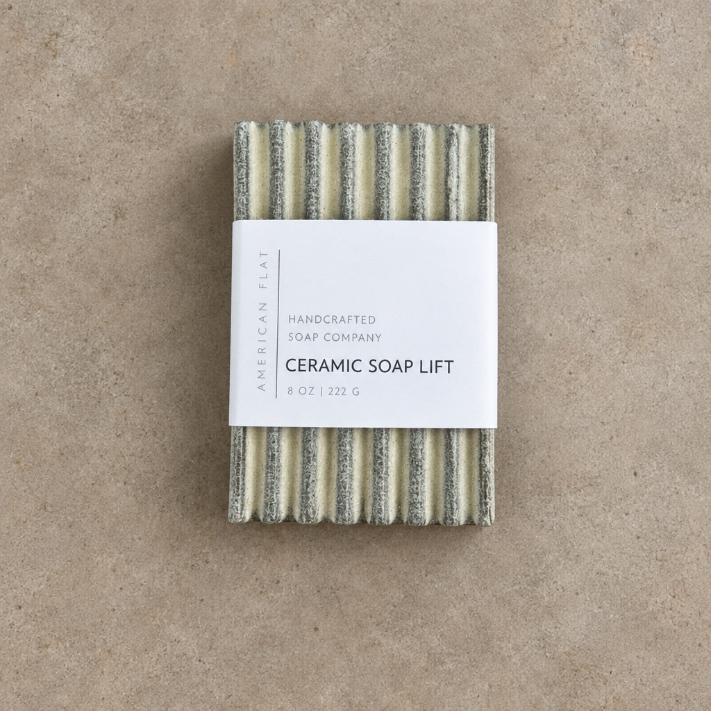 Cream colored ceramic soap lift with grooved top on wood surface