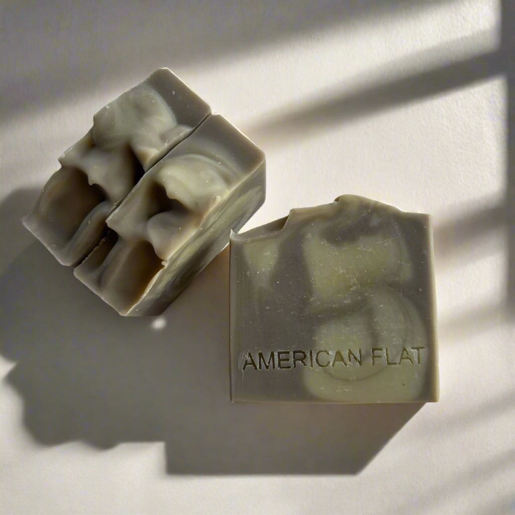 Stack of three Patchouli Lime grey and cream swirled soap bars on white surface