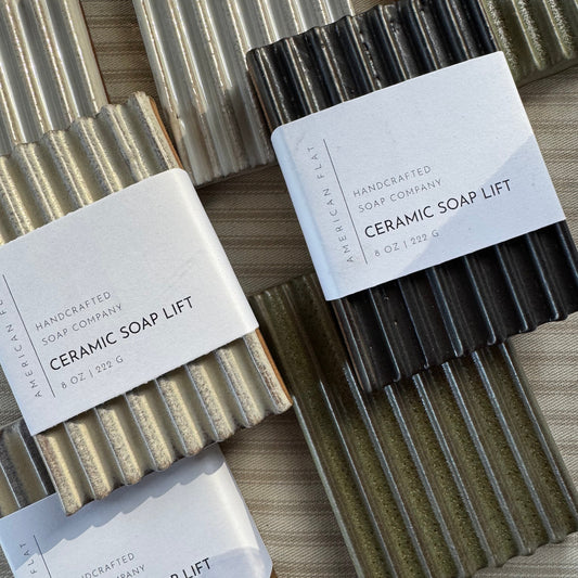 Rectangular and grooved ceramic soap lifts in a variety of colors on a striped surface