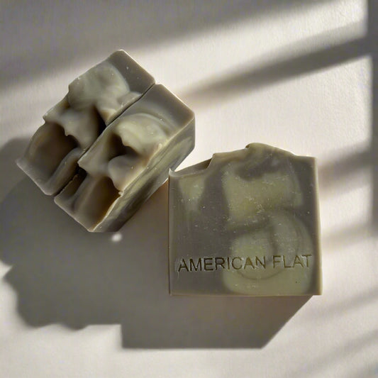 Stack of three Patchouli Lime grey and cream swirled soap bars on white surface