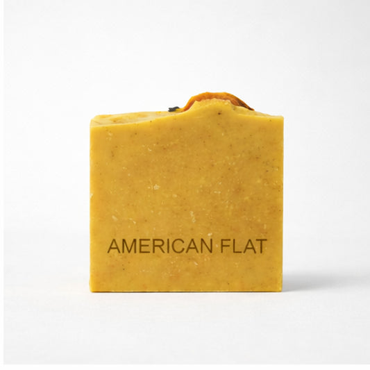 Orange bar of soap with 'American Flat' branding on a white background