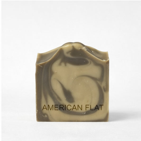 Bar of charcoal and cream swirled soap with 'American Flat' branding on a white background