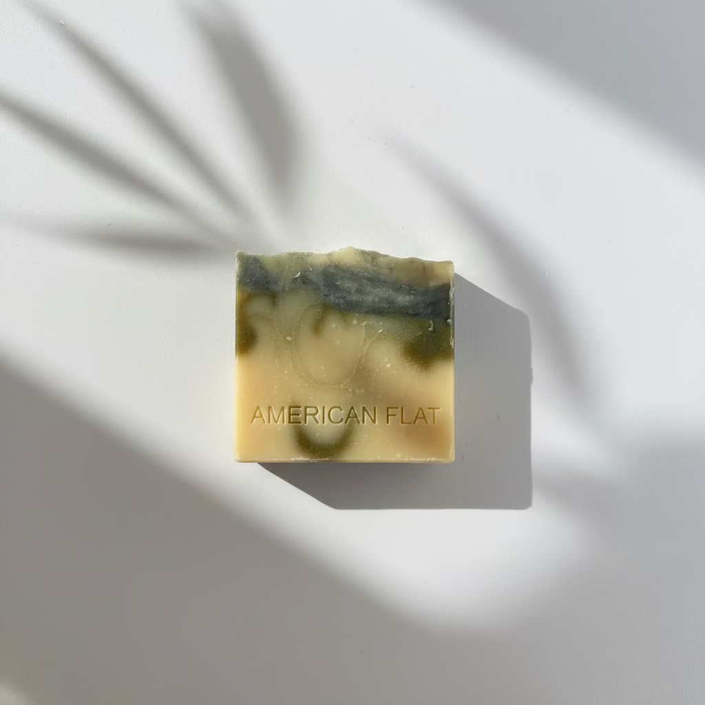 A CREAM COLORED BAR OF SOAP WITH SWIRLS OF GREEN AND BLUE ON A NEUTRAL BACKGROUND