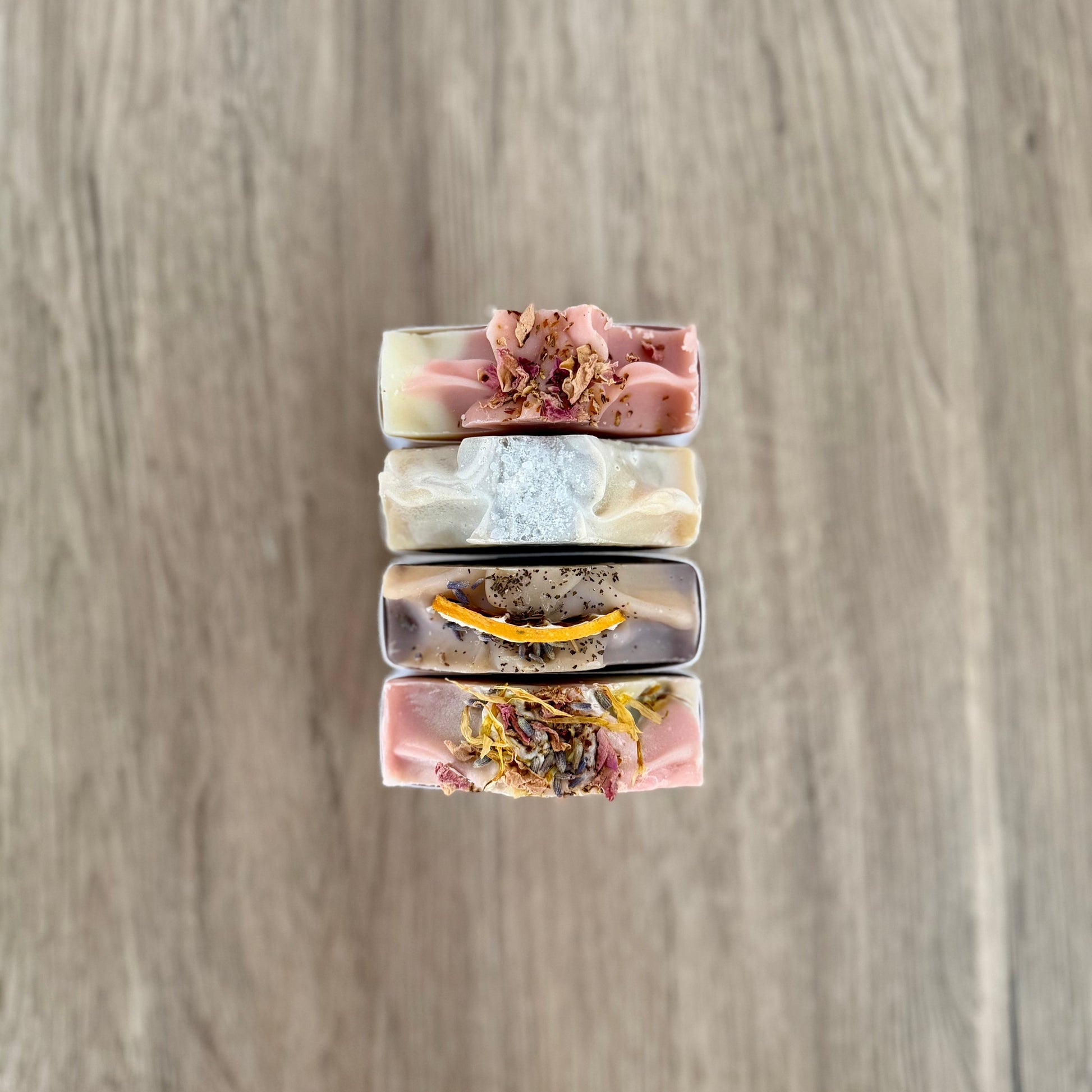 Stack of three soap bars with floral elements on a wooden surface