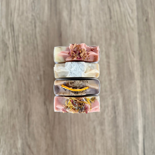 Stack of three soap bars with floral elements on a wooden surface