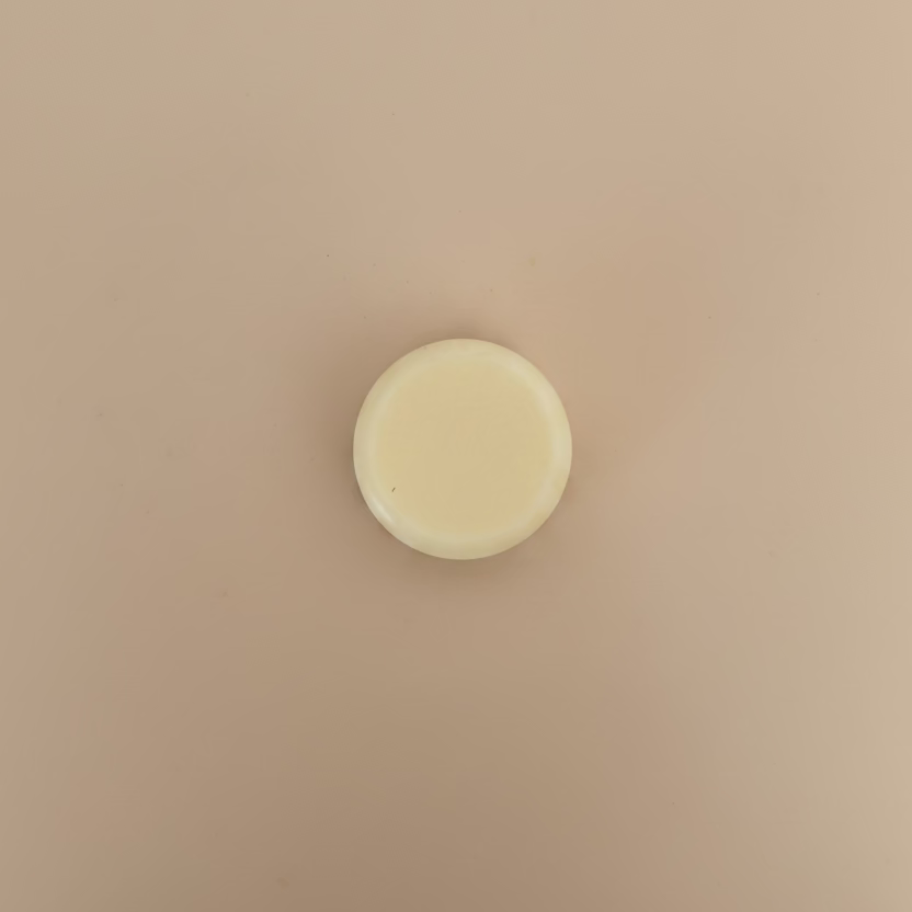 white circular conditioner bar on a soft beige background