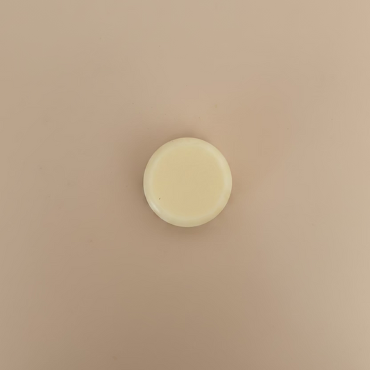 white circular conditioner bar on a soft beige background