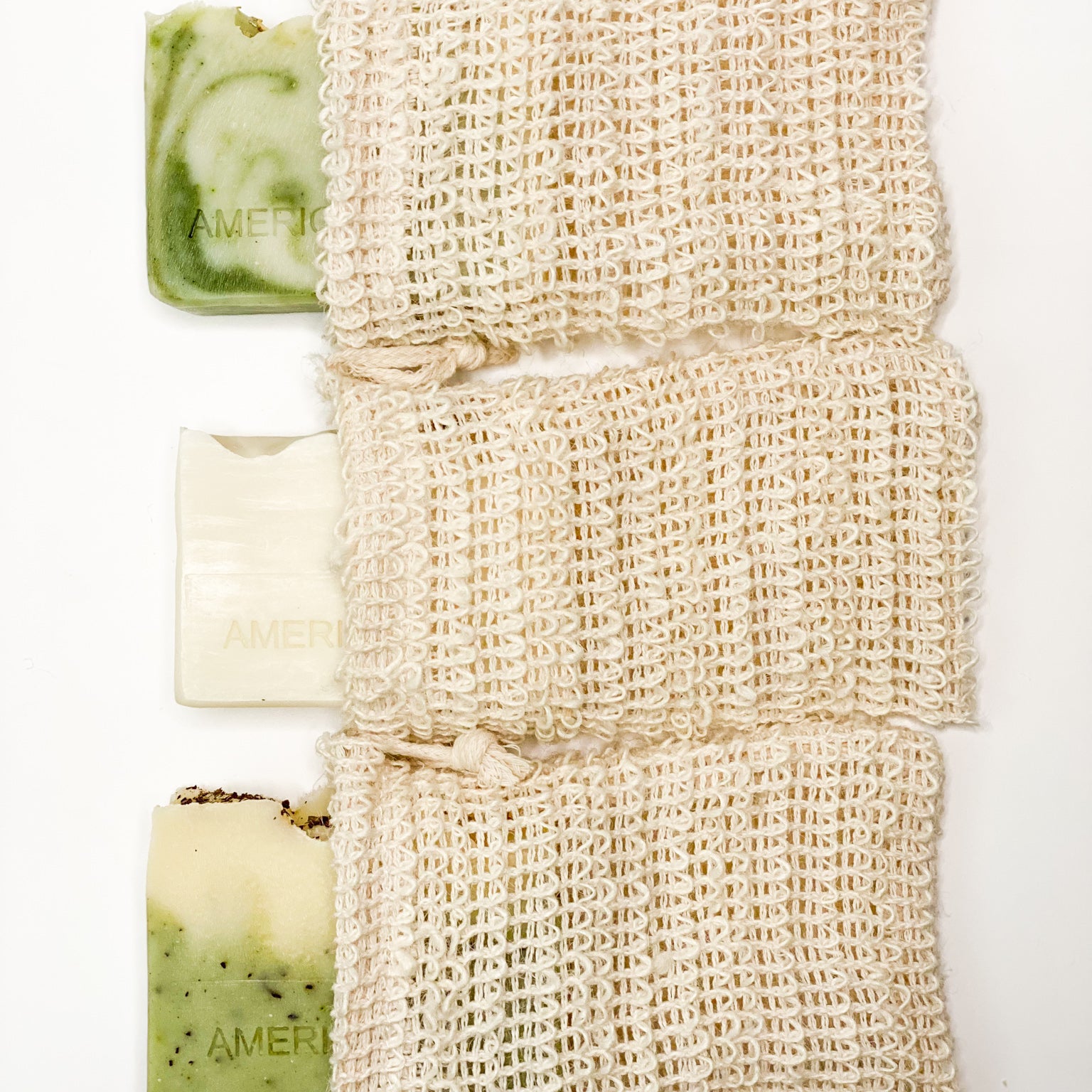 A beige sisal exfoliating bag with a drawstring, displayed alongside a green and white bars of soap.